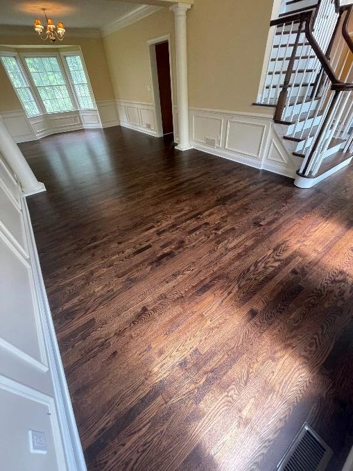 Dark hardwood floor running through a foyer and stair hall